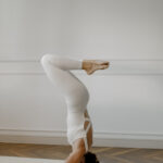 Девушка выполняет стойку на голове в йоге и влияние перевернутых асан на иммунитет